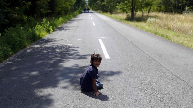 A migrant boy from Syria rests on a road after crossing the border from Serbia to Hungary on Friday.