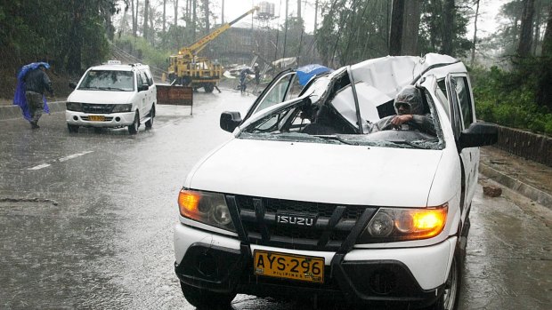 A resident drives a vehicle damaged by a fallen electric post after Typhoon Goni battered Baguio city.