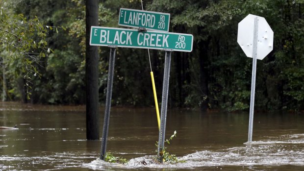 Street signs are surrounded by floodwater from Black Creek in Florence, South Carolina on Monday as flooding continues following several days of rain.