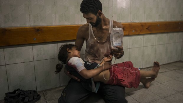 Mohammed Shinbary comforts his daughter Mahasin, 7, who was injured after an attack on a United Nations school.