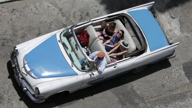 Tourists ride a classic American convertible in Havana, Cuba.