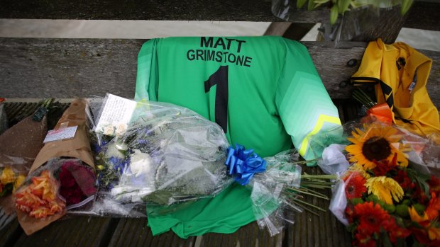 Floral tributes and a football shirt in memory of victim Matt Grimstone are placed on a bridge over the river Adur near where a Hawker Hunter fighter jet crashed in Shoreham, England. T