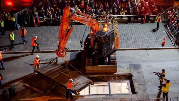 A crane closes over Parr's home for the next three days, as the crowd in Tasmania watches on. 