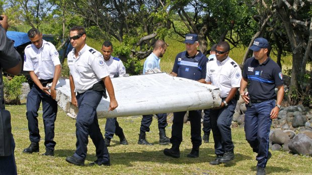 French police officers carry the flaperon after it washed up on a beach in Saint-Andre, Reunion Island, in July. The piece of debris has been identified as coming from Malaysia Airlines MH370.
