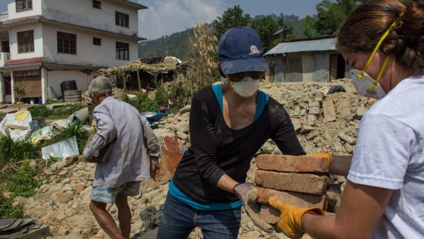 Anika Fletcher helps salvage bricks from the rubble of a house destroyed in the April 25 earthquake, in Baluwa village north of Kathmandu city.