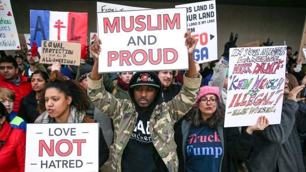 Demonstrators hold signs at Atlanta's airport to denounce President Donald Trump's executive order.