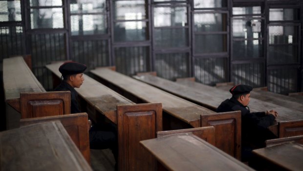 Policemen sit in front of empty holding pens - where defendants normally stand - and benches during the trial of Muslim Brotherhood leaders in Cairo at the weekend.