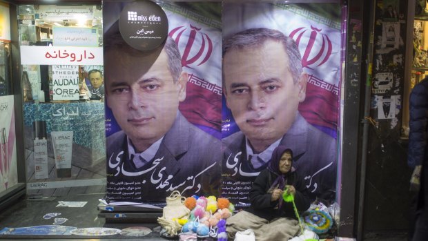 People walk past electoral posters in Tehran, Iran on Friday. 