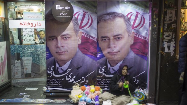 People walk past electoral posters in Tehran, Iran on Friday. 