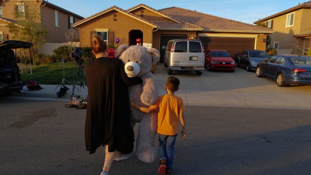 Neighbour Avery Sanchez, 6, walks with his mother, Liza Tozier to drop off his large "Teddy" as a gift for the children who lived on a home where police arrested a couple for torture and neglect.