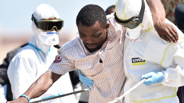 A crew member of the Irish naval vessel LE Niamh helps a migrant disembark at Messina harbour in Sicily on Monday.