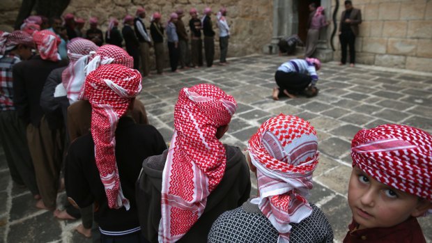 Yazidi boys line up to pray at their religion's holiest temple last week in the Nineveh Province village of Lalish, Iraq.