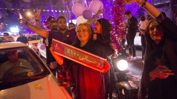 Supporters of President Hassan Rouhani celebrate his re-election holding a sign that reads "Rouhani 100%".