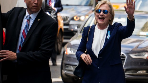 Democratic presidential candidate Hillary Clinton waves as she walks from her daughter's apartment building on September 11, 2016, in New York, two hours after the incident.