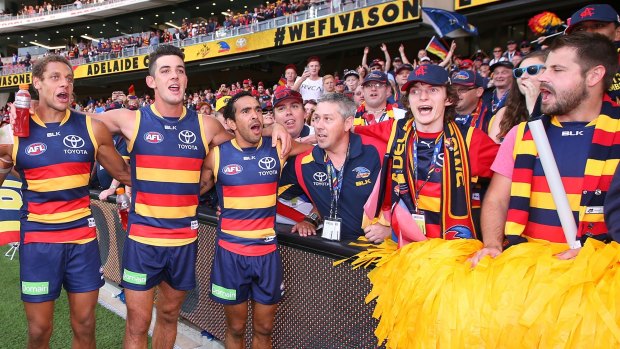 Adelaide players Cam Ellis-Yolmen, Taylor Walker and Eddie Betts sing the club song with fans after the match against North Melbourne in round one.