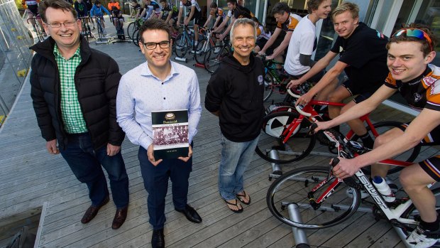 Author and club historian Ben Schofield, president Ag Giramondo, holding the book, and roller coach Cameron McFarlane at the Brunswick Velodrome with cyclists. 