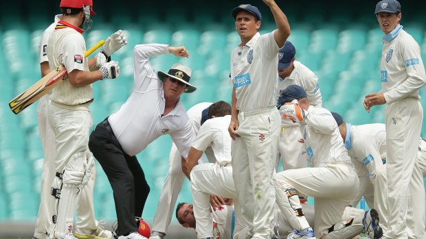 Teammates and opponents rush to help Phillip Hughes after he was struck in the head by a deliver on day one of the Sheffield Shield.