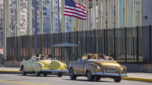 Tourists in vintage American convertibles as they drive past the recently-opened US embassy in Havana.
