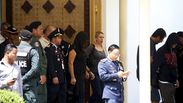 Three of the four refugees transferred to Nauru are surrounded by Cambodian police officers as they arrive at Phnom Penh International Airport in June.