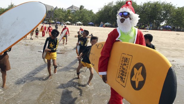 An Indonesian surf instructor dressed as Santa Claus at Kuta beach in Bali, Indonesia.