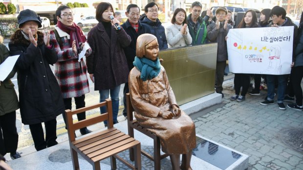 Members of a civic group unveil a statue symbolising women forced into wartime military brothels in front of the Japanese Consulate in Busan, South Korea, in December.