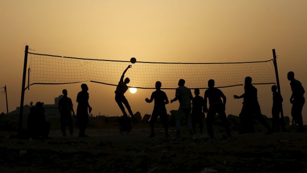 Palestinians play volleyball near the ruins of houses that witnesses said were destroyed by Israeli shelling during a 50-day war last year.