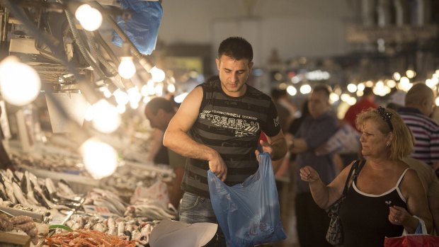 A customer, right, buys fresh fish from a vendor at Varvakeios fish and meat market in Athens  last week.