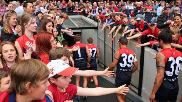 Reaching out: The Melbourne faithful embrace their conquering heroes at the MCG on Saturday.