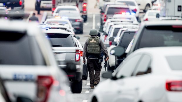 An officer walking between a large number of police vehicles in Southeast Washington. An official had said shots were reported in a building on the Washington Navy Yard campus. 