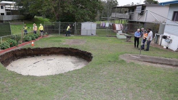 Council workers inspect the massive hole.