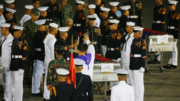 A military chaplain blesses the flag-draped caskets of eight of the thirteen marines killed Friday in the battle with Muslim militants in Marawi city in southern Philippines