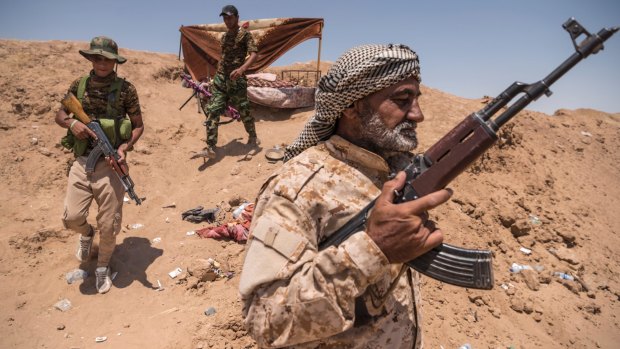 Shiite militia fighters walk along the Syrian border outside al-Badi, Iraq, earlier this year. 