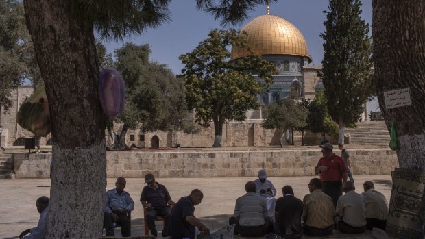 Locals sit near the Dome of the Rock in the Israeli-occupied Old City of Jerusalem.