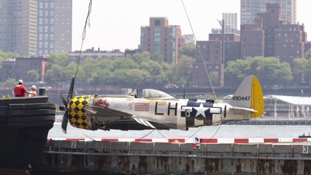 Officials place the World War II vintage P-47 Thunderbolt aircraft on the Wall Street Heliport pier after removing it from the Hudson River. Pilot William Gordon died in the crash