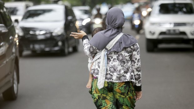 Yanti, carrying her child, seeking work as a "jockey" in Jakarta on Wednesday. 