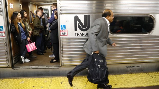 An afternoon rush hour commuter rushes to board a crowded NJ Transit train at Penn Station in New York.