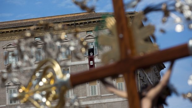 Pope Francis is framed by a crucifix as he delivers his speech from his studio window overlooking St Peter's Square at the Vatican on Sunday.
