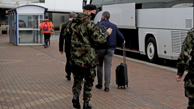 A passenger is escorted to the Crowne Plaza hotel for quarantine in Dublin, Ireland.