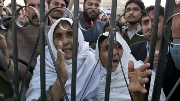 Pakistani family members wait outside a local hospital where injured students were taken.