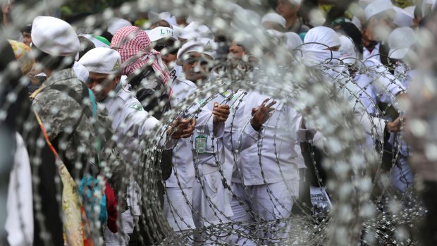 Muslim protesters are seen through razor wire barricades during a rally against the persecution of Rohingya Muslims outside the Myanmar's Embassy in Jakarta, Indonesia last week.