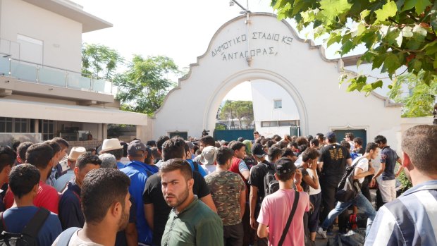 Syrian migrants wait to enter a stadium in Kos to register as refugees.
