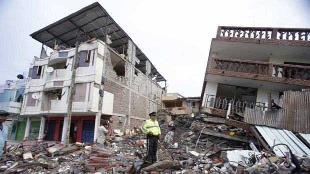 A police officer stands on debris, next to buildings destroyed by an earthquake in Pedernales, Ecuador, on Sunday. 