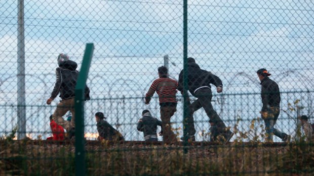 Migrants run on the railway as they attempt to access the Channel Tunnel, in Calais, on Wednesday. 