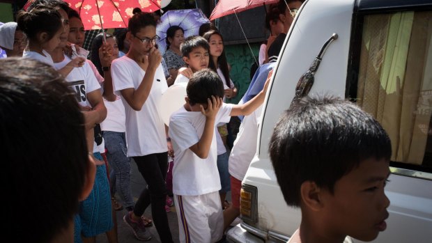 Children and relatives mourn while walking behind a hearse during a funeral held for Alex Hongco killed in a police drugs raid in December.