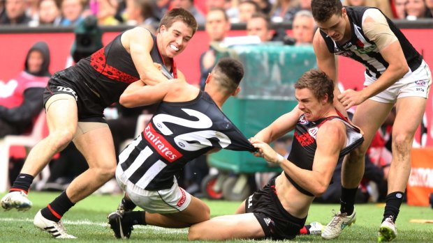 A melee breaks out as Marley Williams of the Magpies is dragged down by Zach Merrett and Joe Daniher of the Bombers.