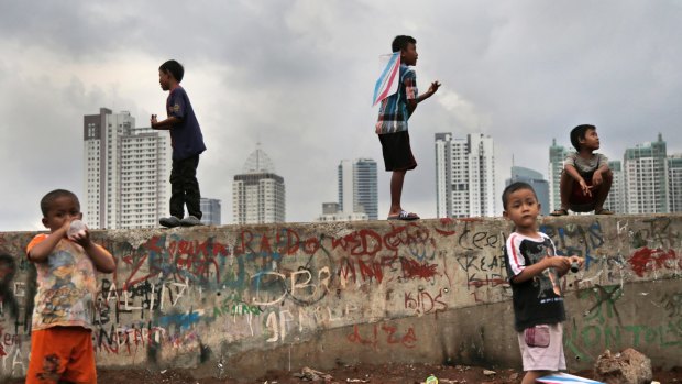 Children play against the Jakarta skyline.