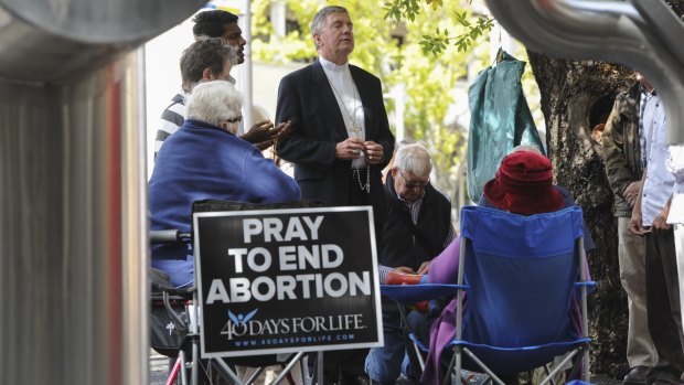 Catholic Archbishop of Canberra and Goulburn Christopher Prowse, centre, attends a prayer vigil outside the Moore Street abortion clinic in 2015.