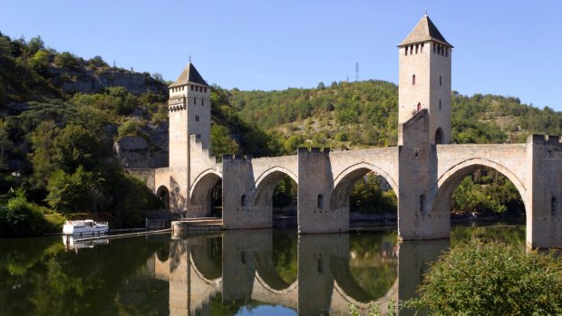 A boat enters the lock under the historic Pont Valentre fortified bridge.