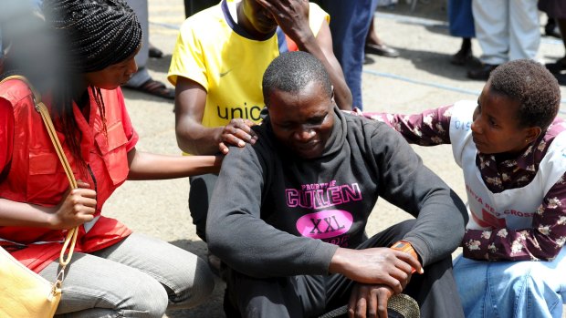 A relative is assisted by Red Cross staff as bodies of the students killed in Thursday's attack by gunmen, arrive at the Chiromo Mortuary.