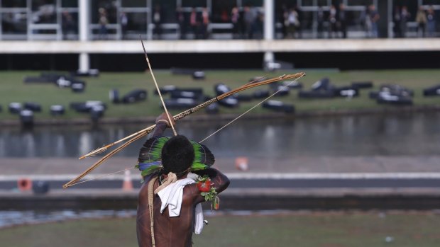 An indigenous man aims his arrow at police during a protest outside the National Congress in Brasilia, Brazil, on Tuesday.